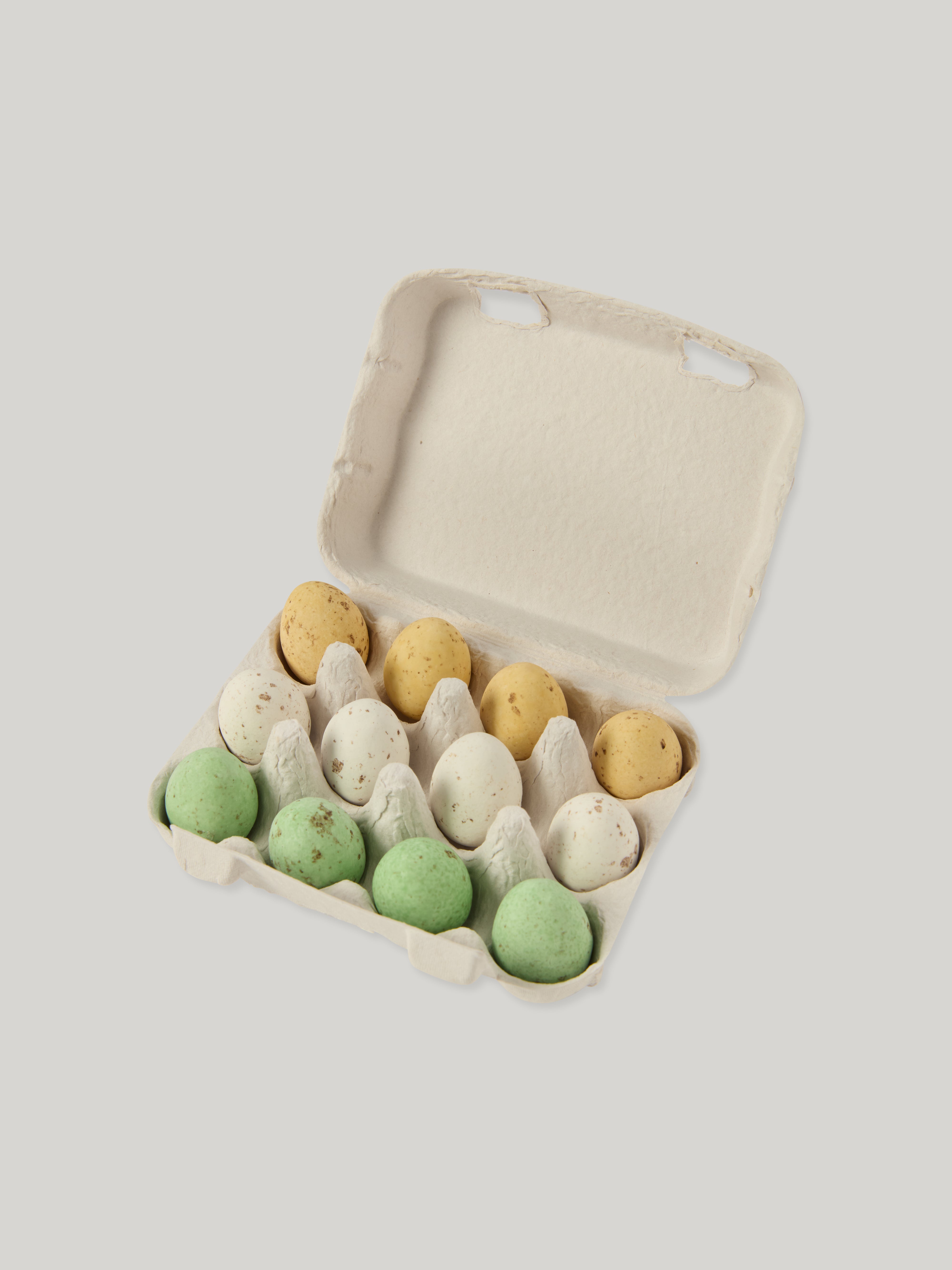 Carton of colorful eggs on a light gray background
