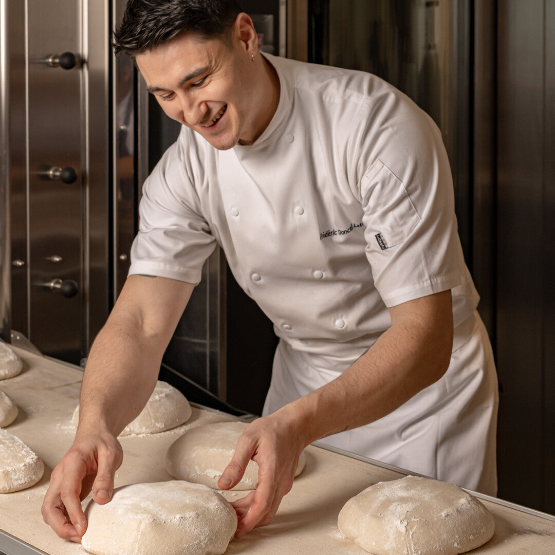 Baker in a professional kitchen handling dough